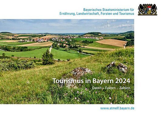 Landschaft mit grünen Wiesen, Feldern und Dorf, Titel „Tourismus in Bayern 2024“ vom Bayerischen Staatsministerium