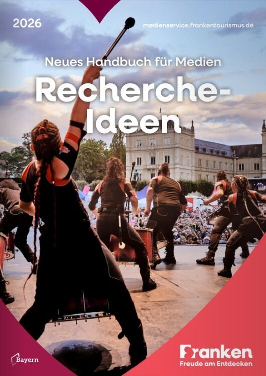 Menschen mit Trommeln auf einer Bühne vor großem Publikum vor einem Schloss, Text zu Recherche-Ideen 2026