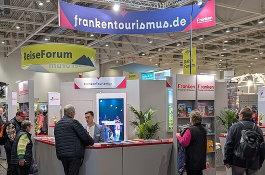Messestand des Tourismusverbandes Franken mit mehreren Personen und Informationsmaterial auf einem Messegelände