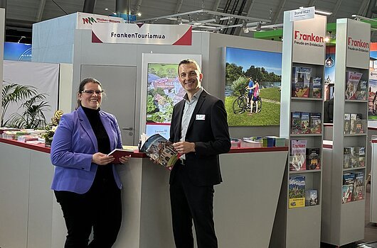Franken-Stand bei der Messe CMT in Stuttgart Messestand des Tourismusverband Franken mit zwei Personen, Informationsmaterial und Werbebannern in einer Halle