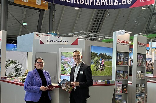 Franken-Stand bei der Messe CMT in Stuttgart Messestand des Tourismusverband Franken mit zwei Personen, Informationsmaterial und Werbebannern in einer Halle