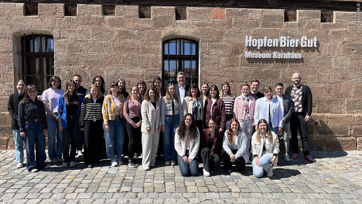 Gruppenfoto von 28 Personen vor einem Gebäude mit der Aufschrift „Hopfen Bier Gut Museum Kornhaus“.