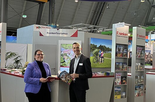 Franken-Stand bei der Messe CMT in Stuttgart Messestand des Tourismusverband Franken mit zwei Personen, Informationsmaterial und Werbebannern in einer Halle