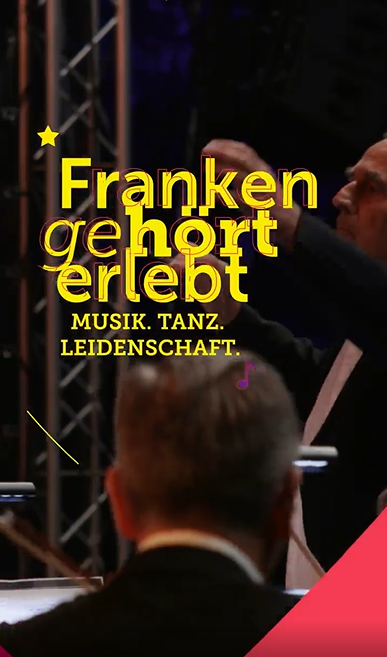 Zwei Männer dirigieren ein Orchester, Text „Franken gehört erlebt Musik. Tanz. Leidenschaft.“ in gelber Schrift.