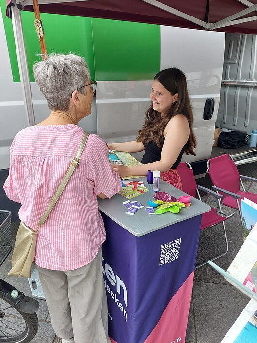 Im Beratungsgespräch bei der Frankentour Baden-Württemberg 2026, Reutlingen Zwei Frauen an einem Infostand mit Flyern und kleinen Gegenständen, im Hintergrund ein weißes Fahrzeug.